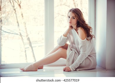 Beautiful Young Woman With Blue Eyes And Bare Legs Sitting Near Window