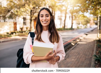 Beautiful Young Woman With Book Going To College. Young Female University Student With Book In Campus.