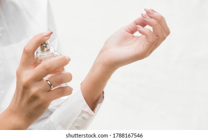 Beautiful young woman with a bottle of perfume on a light background, hands of a girl close-up. Perfumes and aromatherapy. The concept of beauty. - Powered by Shutterstock