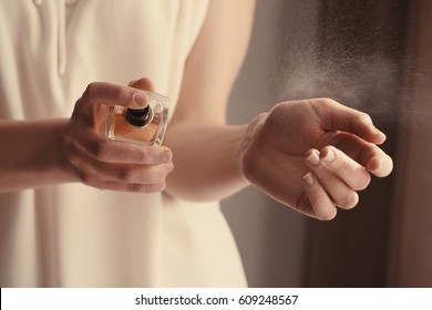 Beautiful young woman with bottle of perfume at home, closeup