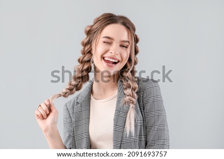 Beautiful young woman with braided hair on grey background Stock photo © 