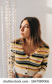 Beautiful Young Woman In Bright Living Room With White Walls And Iridescent Curtain