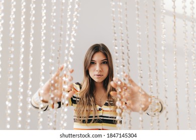 Beautiful Young Woman In Bright Living Room With White Walls And Iridescent Curtain