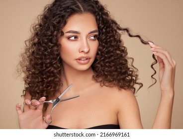 Beautiful Young Woman With A Bright Makeup And A Afro  Hair Holds Metal Scissors. Model With Curly Hair. Hair Salon, Haircut. Care And Beauty Hair Products. Perfect Make-up