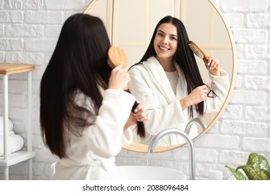 Beautiful Young Woman Brushing Hair In Bathroom