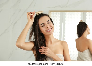 Beautiful Young Woman Brushing Wet Hair At Home