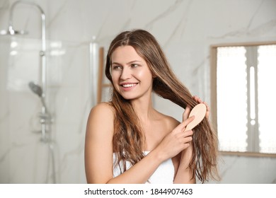 Beautiful Young Woman Brushing Wet Hair In Bathroom