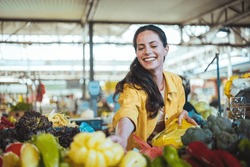 Beautiful Young Woman Buying Vegetables. Young Cheerful Woman At The Market. Raw Food, Veggie Concept. Portrait Of Smiling Good Looking Girl In Casual Clothing