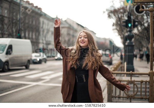 Beautiful young\
woman calling a taxi on the\
street.