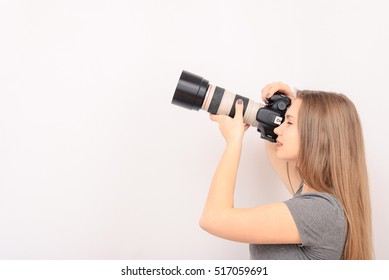 Beautiful Young Woman With Camera. Full Isolated Woman With Dslr. Woman Holding A Camera - Isolated Over A White Background. Professional Female Fashion Photographer Taking A Snapshot.