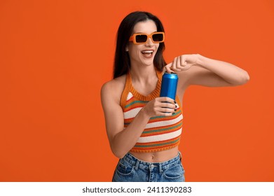 Beautiful young woman with can of cold beer on orange background - Powered by Shutterstock