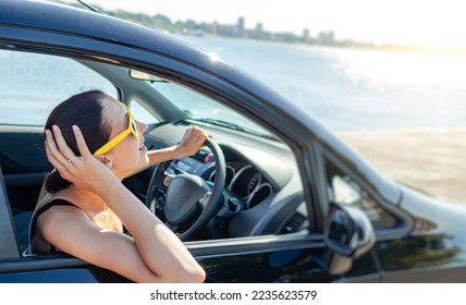 Beautiful young woman in a car smiling in yellow sunglasses against the backdrop of the sea. - Powered by Shutterstock