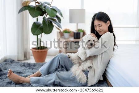 Beautiful young woman in casual clothes playing with her beloved pet at home.