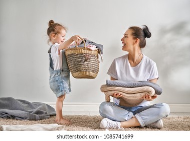 Beautiful young woman and child girl little helper are having fun and smiling while doing laundry at home. - Shutterstock ID 1085741699