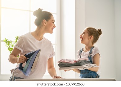 Beautiful young woman and child girl little helper are having fun and smiling while ironing at home. - Powered by Shutterstock