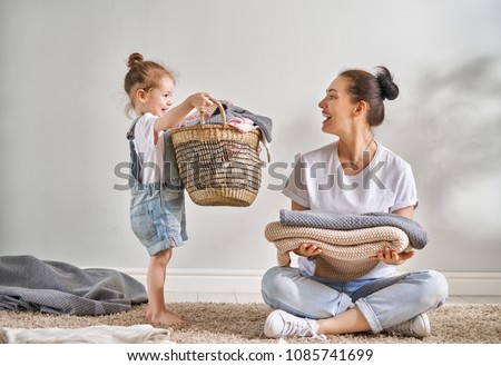 Beautiful young woman and child girl little helper are having fun and smiling while doing laundry at home. Stock photo © 
