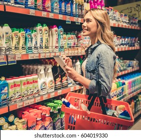 Beautiful Young Woman Is Choosing Household Products And Smiling While Doing Shopping At The Supermarket