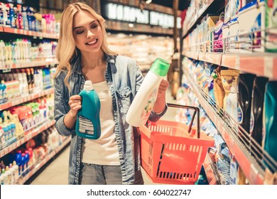 Beautiful Young Woman Is Choosing Household Products And Smiling While Doing Shopping At The Supermarket