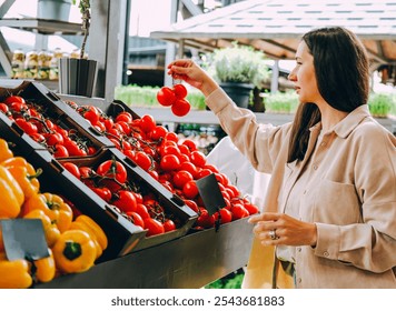 Beautiful young woman choosing tomatoes on local farmer's market. - Powered by Shutterstock