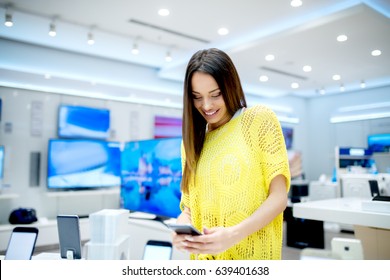 Beautiful Young Woman Choosing Which Smart Phone To Buy. Shopping In Tech Store.