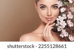 Beautiful young woman with clean fresh skin touching her face in flowers  . Girl facial  treatment   . Cosmetology , beauty  and spa . Female  model, care concept 