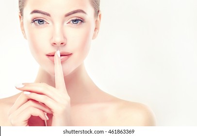 Beautiful Young Woman With Clean Fresh Skin  Touch Her Lips. Facial  Treatment   . Cosmetology , Beauty  And Spa . A Secret Or A Surprise ,the Model Holds A Finger To Her Mouth