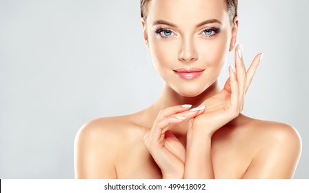 Beautiful Young Woman with Clean Fresh Skin  touch own face . Facial  treatment   . Cosmetology , beauty  and spa . - Shutterstock ID 499418092