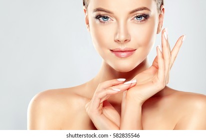 Beautiful Young Woman with Clean Fresh Skin  touch own face . Facial  treatment   . Cosmetology , beauty  and spa .