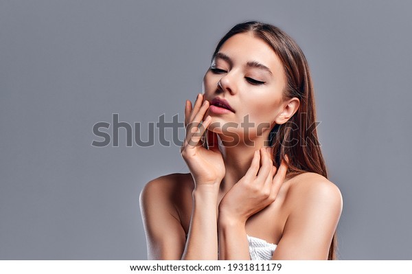 Beautiful young woman with clean\
perfect skin. Portrait of beauty model with natural nude makeup.\
Spa, skin care and wellness. Close up, gray background,\
copyspace.