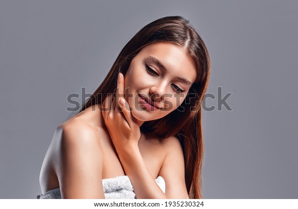 Beautiful young woman with clean
perfect skin. Portrait of beauty model with natural nude makeup.
Spa, skin care and wellness. Close up, gray background,
copyspace.
