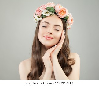Beautiful young woman with clear skin portrait. Pretty girl with long curly hair and flowers. Skincare and facial treatment concept