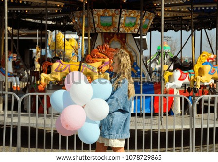 Beautiful young woman with colorful balloons in the amusement park 