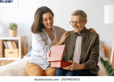 Beautiful young woman congratulating father and giving to him a gift.   - Powered by Shutterstock