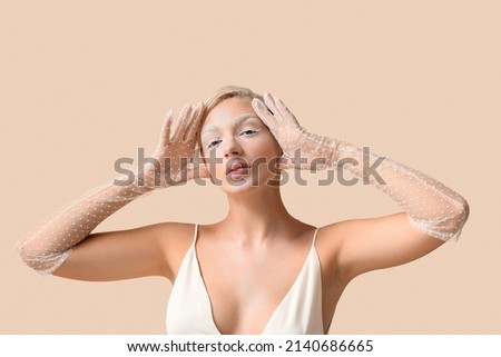 Beautiful young woman with creative makeup and elegant gloves on light background