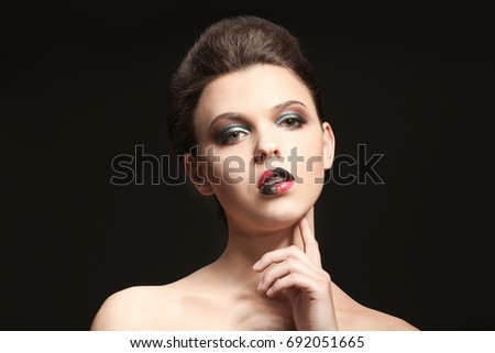 Beautiful young woman with creative makeup on dark background