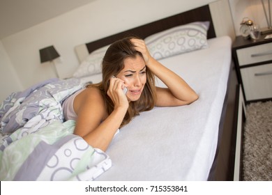 Beautiful Young Woman Crying On The Phone In Her Bed