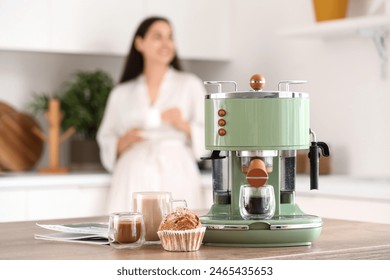 Beautiful young woman with cups of coffee, cupcake and modern machine in kitchen - Powered by Shutterstock