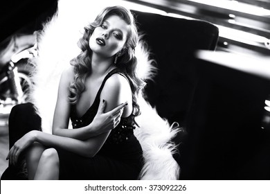 beautiful young woman with curly blond hair and bright makeup. Fashion studio shot. Retro fashion. Black and white image