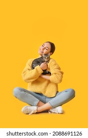 Beautiful young woman with cute cat on color background