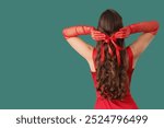 Beautiful young woman with cute Christmas bow in her hair on green background, back view