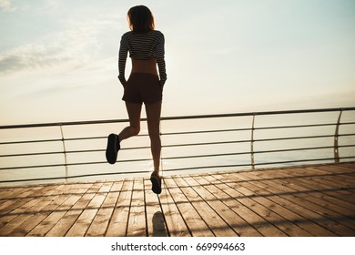 beautiful young woman dance on sunset or sunrise from a ship or dock