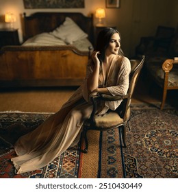 Beautiful young woman with dark brown hair in sheer nightgown and lace robe posing in an antique bedroom in boudoir style