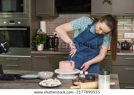 beautiful young woman decorating a cake homemade cake in the kitchen
