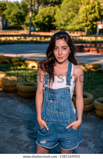 Beautiful young woman in denim overalls on the\
go-kart track