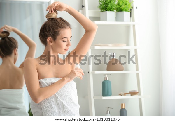 Beautiful young\
woman with deodorant in\
bathroom