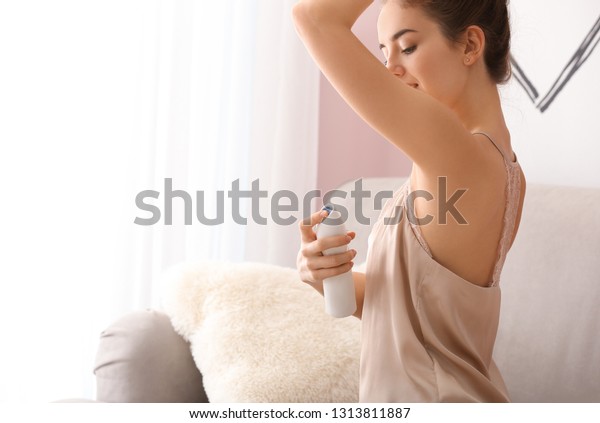Beautiful young woman\
with deodorant at\
home
