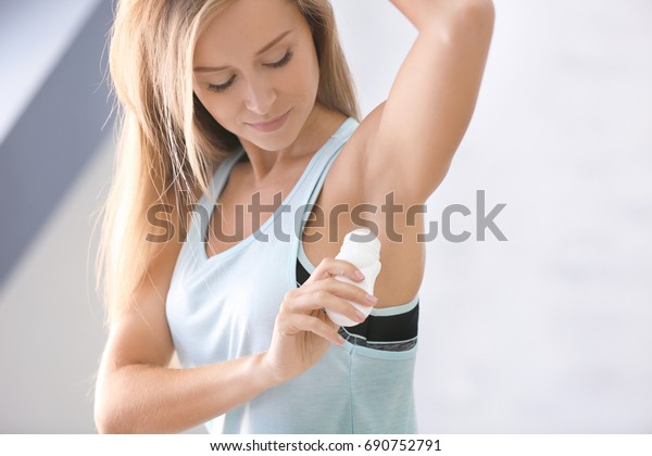 Beautiful young woman
with deodorant at
home