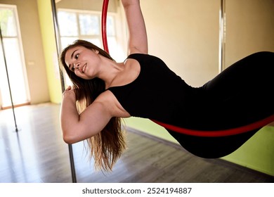 Beautiful young woman doing acrobatics on an aerial hoop while wearing a dancing costume. - Powered by Shutterstock