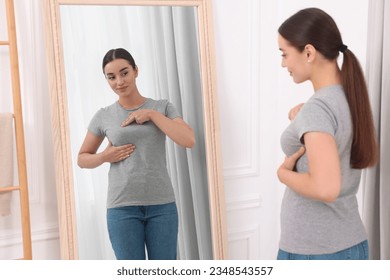 Beautiful young woman doing breast self-examination near mirror indoors - Powered by Shutterstock