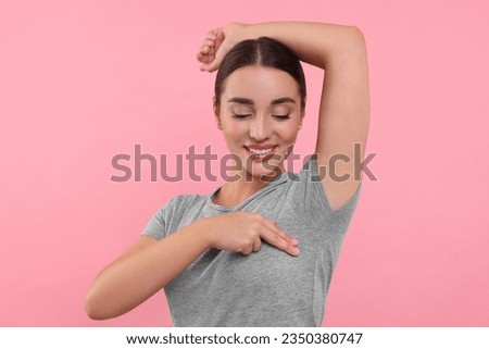 Beautiful young woman doing breast self-examination on pink background